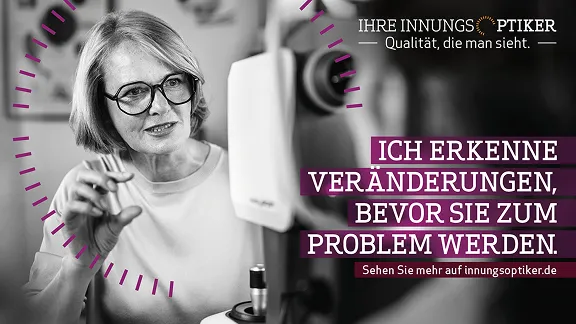 Eine lächelnde Frau mit kurzen, hellen Haaren und Brille blickt direkt in die Kamera und gestikuliert mit der Hand, als würde sie etwas erklären. Sie befindet sich in einer professionellen Umgebung, wahrscheinlich einem Optikergeschäft, mit Untersuchungsgeräten im Hintergrund. Der Text lautet: „ICH ERKENNE VERÄNDERUNGEN, BEVOR SIE ZUM PROBLEM WERDEN.“